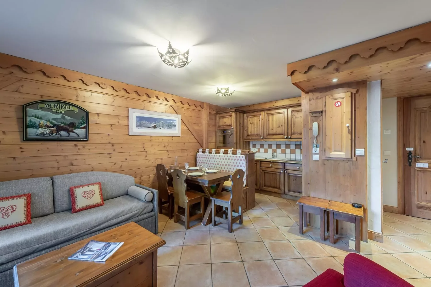 Sala y comedor con paredes de madera, asientos, una mesa y armarios de cocina.