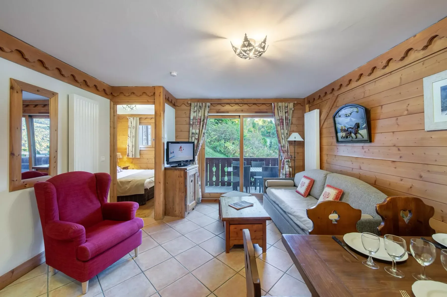 A wood-paneled living room with seating and glass doors opening onto a balcony.