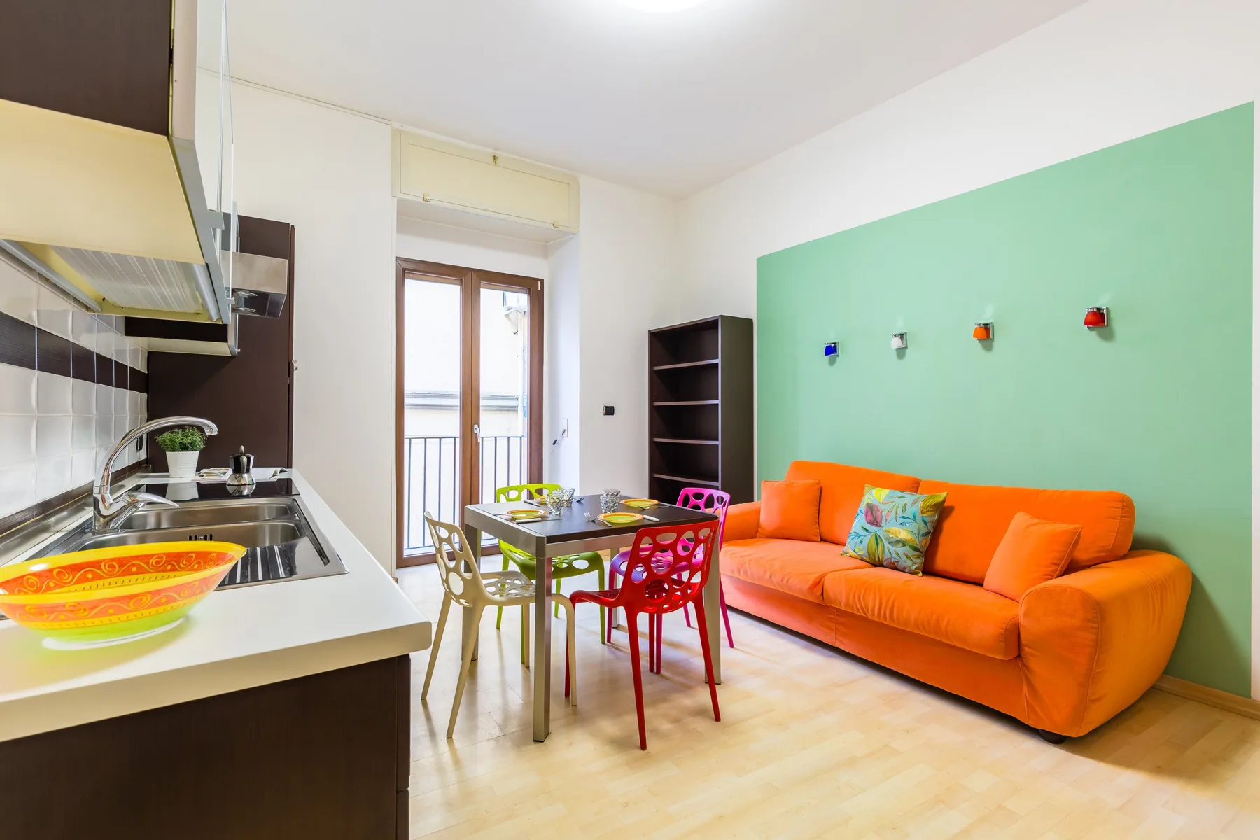 A bright living and dining area with an orange sofa and a small table.