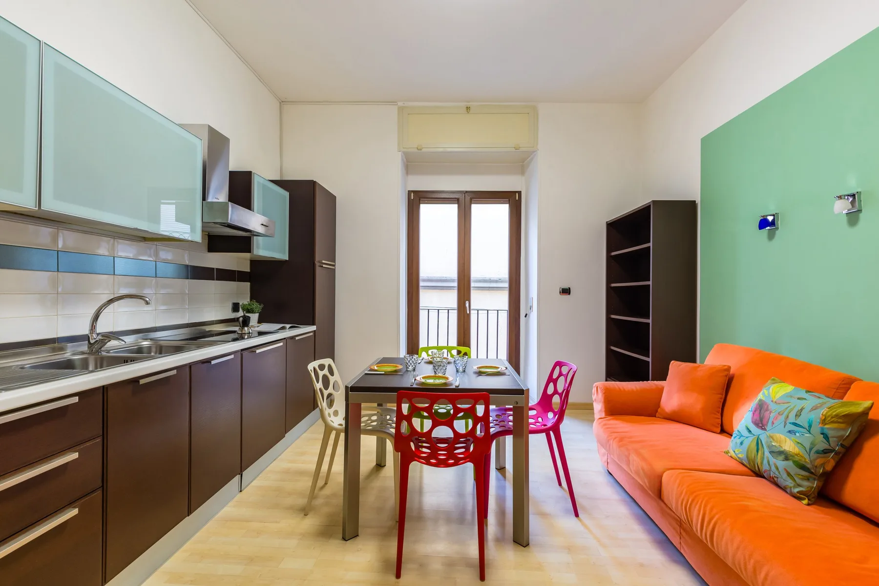 A kitchen and dining area with a table and bright orange seating.
