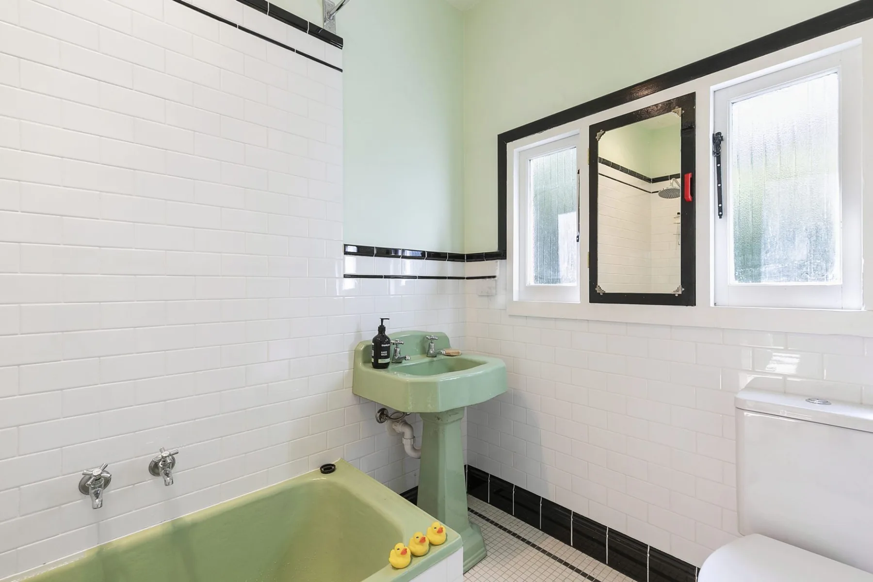 Un baño con una bañera verde pálido y un lavabo a juego.