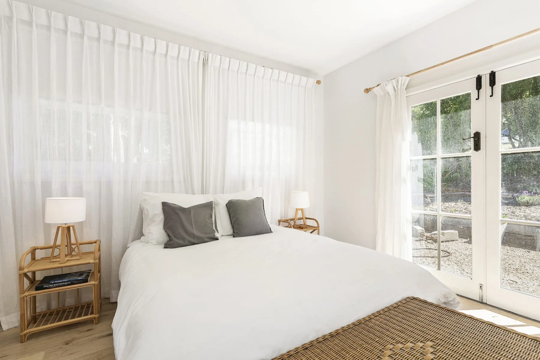 Un dormitorio luminoso con una cama bien tendida y puertas de cristal.