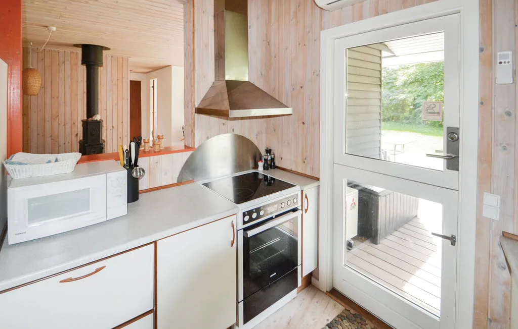 A compact kitchen with a cooktop and oven beside a glass door.