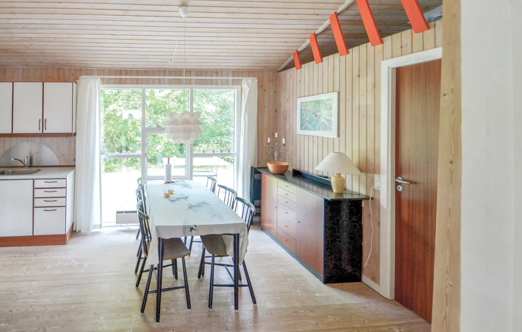 A dining area with a long table beside a compact kitchen.