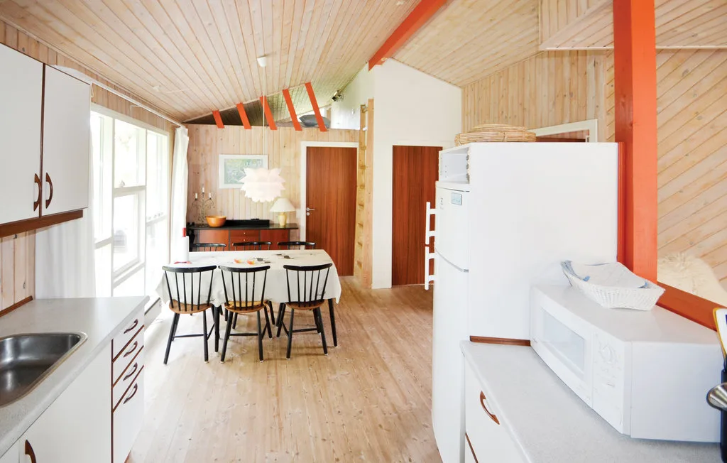 Una cocina y comedor luminosos con una mesa y electrodomésticos blancos.