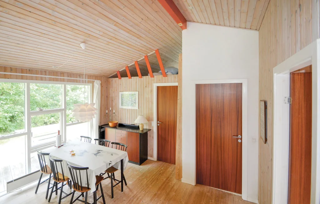 A bright wood-paneled dining area has a table beside large windows.