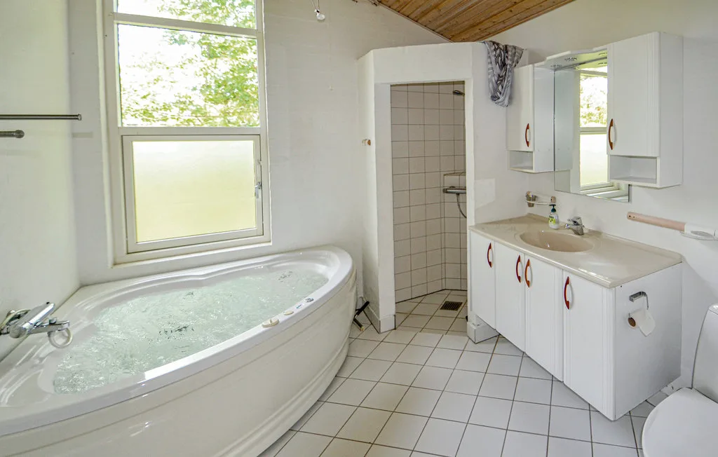 A bathroom with a corner bathtub, sink, and tiled floor.