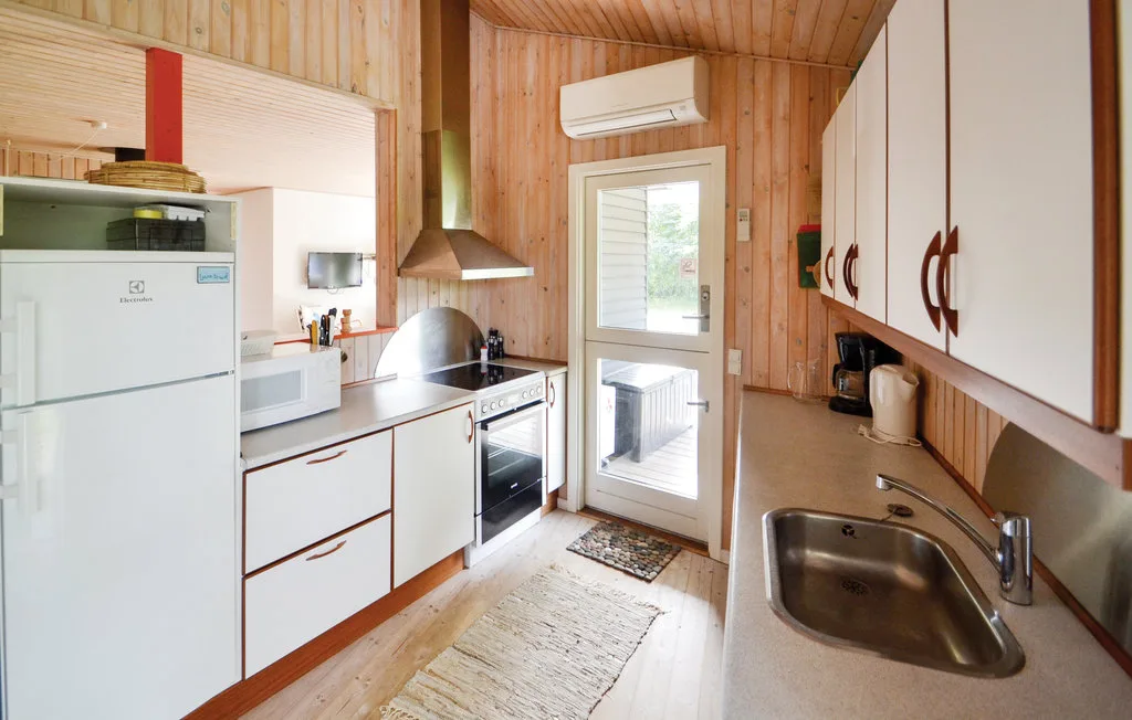 A compact kitchen with white cabinets, a refrigerator, and a sink.