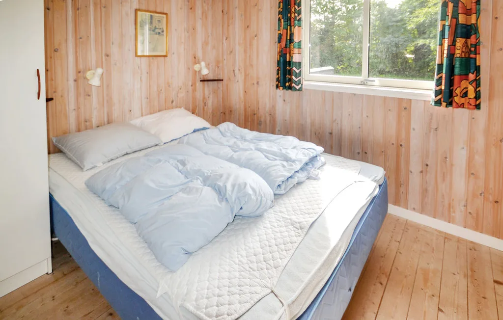A bedroom with an unmade bed beside a window.