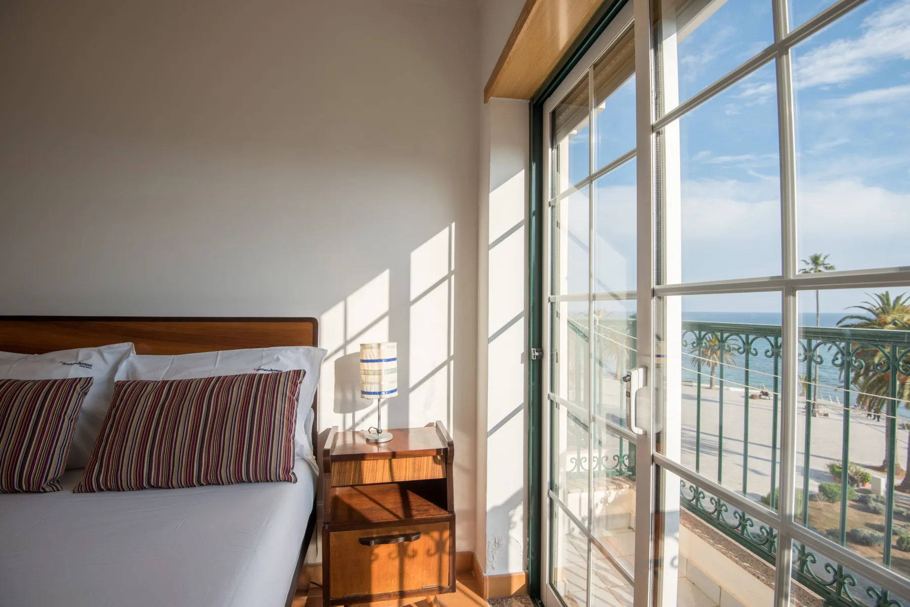 Un dormitorio con una cama junto a grandes ventanales con vistas al mar.