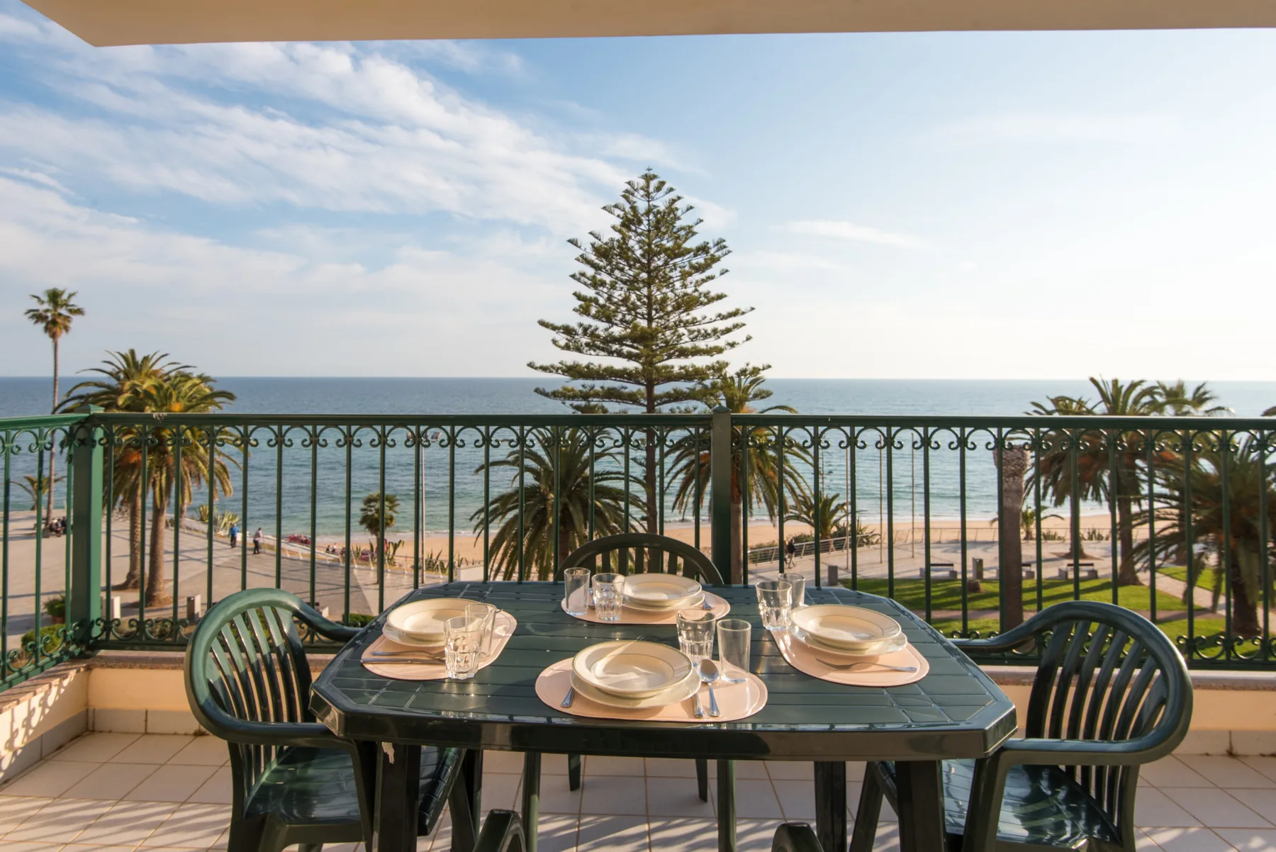 Una mesa de comedor en la terraza está junto a una barandilla con vistas al océano.