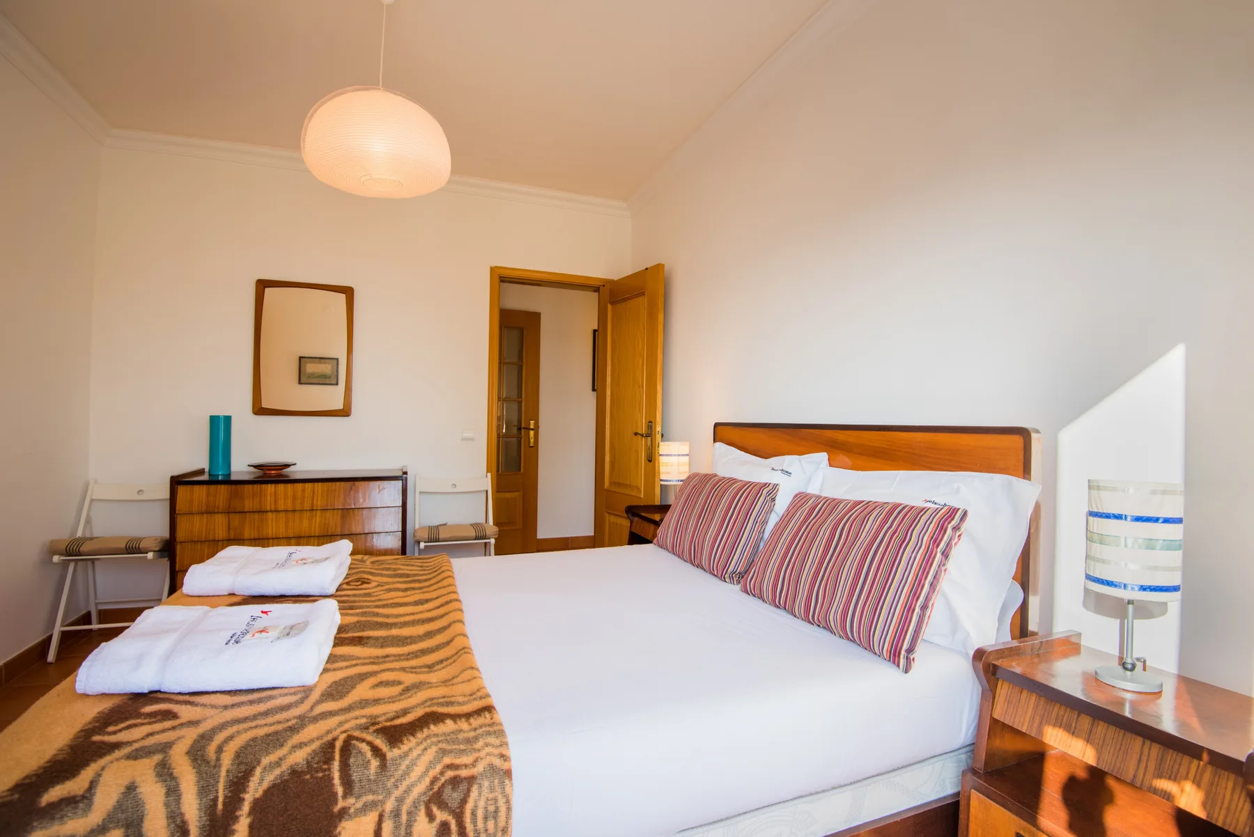 Dormitorio con una cama bien tendida y almohadas a rayas.