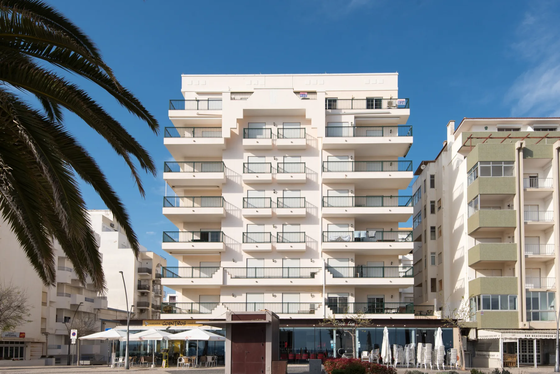 Un edificio de apartamentos de varias plantas con balcones está junto a otros edificios.