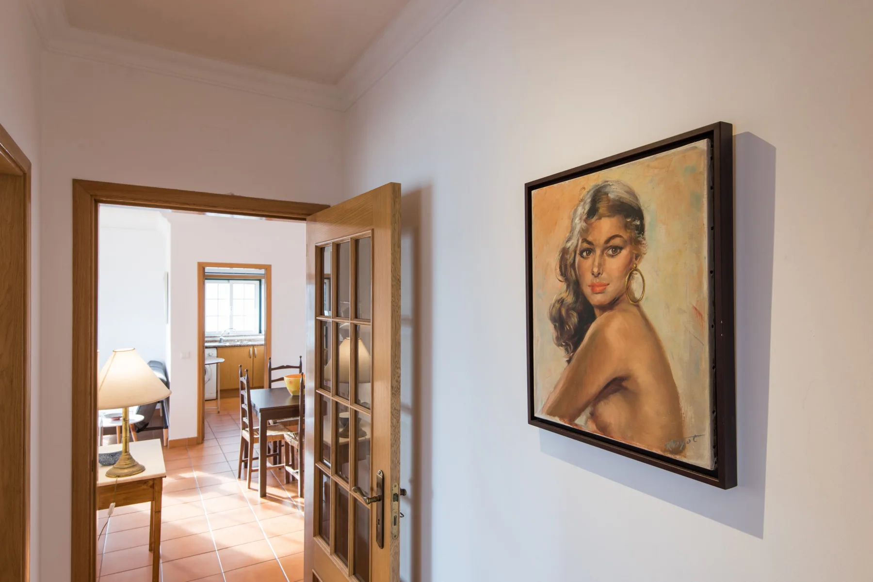 Un pasillo da a un comedor, con un retrato enmarcado en la pared.