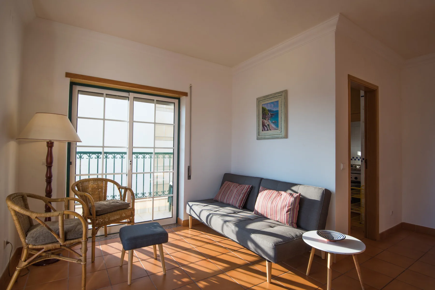 Una sala de estar con asientos junto a una ventana soleada y un balcón.