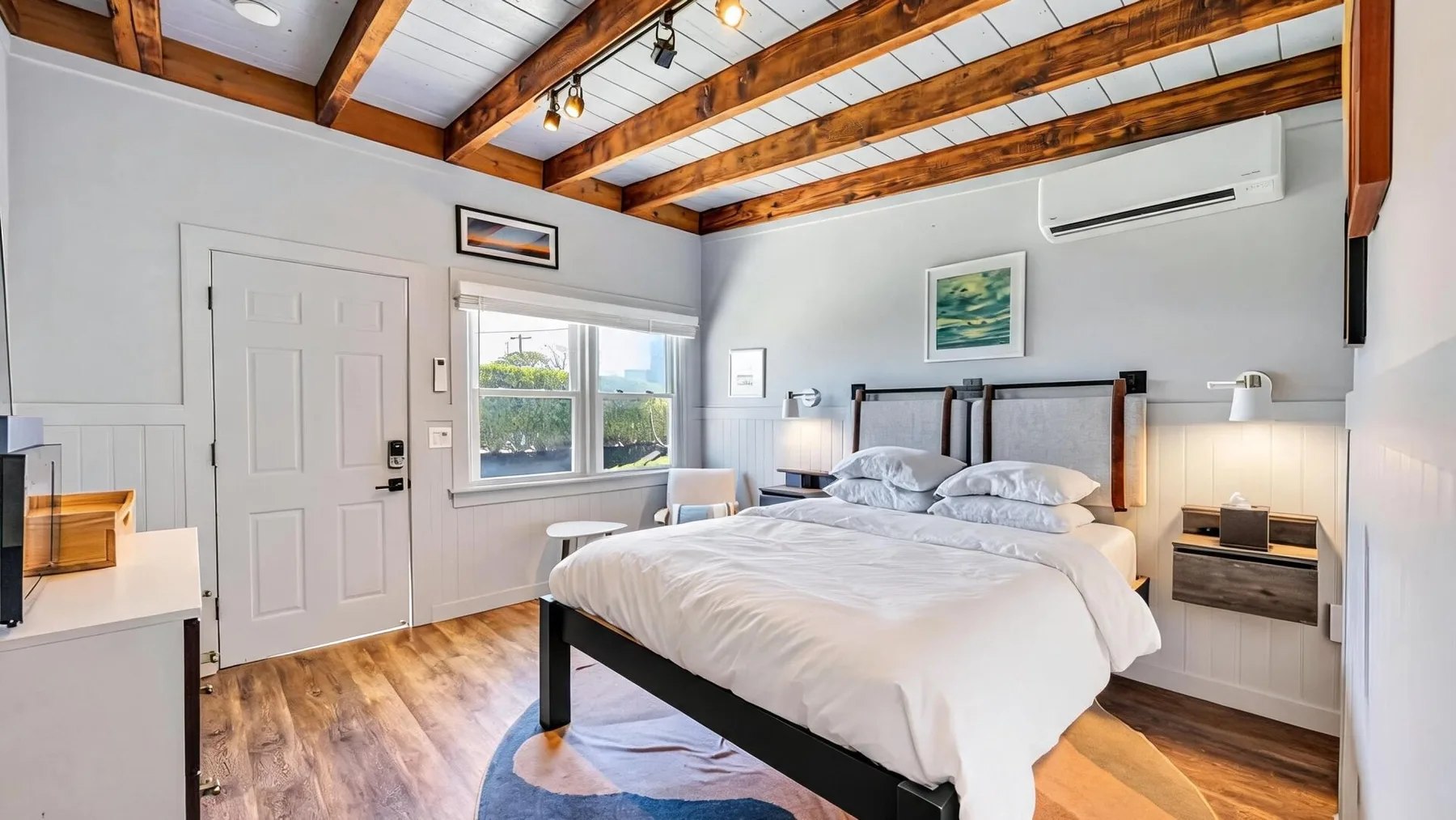 Un dormitorio con una cama bajo vigas de madera a la vista.