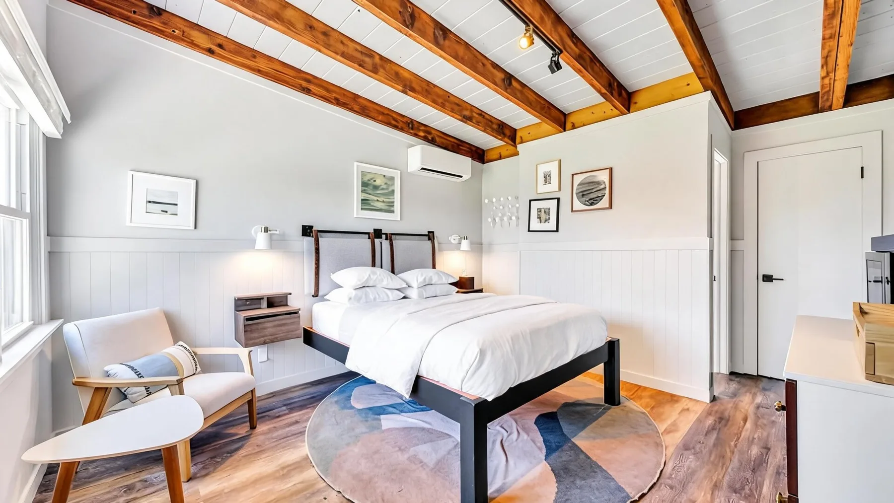 Un dormitorio luminoso con una cama bajo vigas de madera expuestas en el techo.