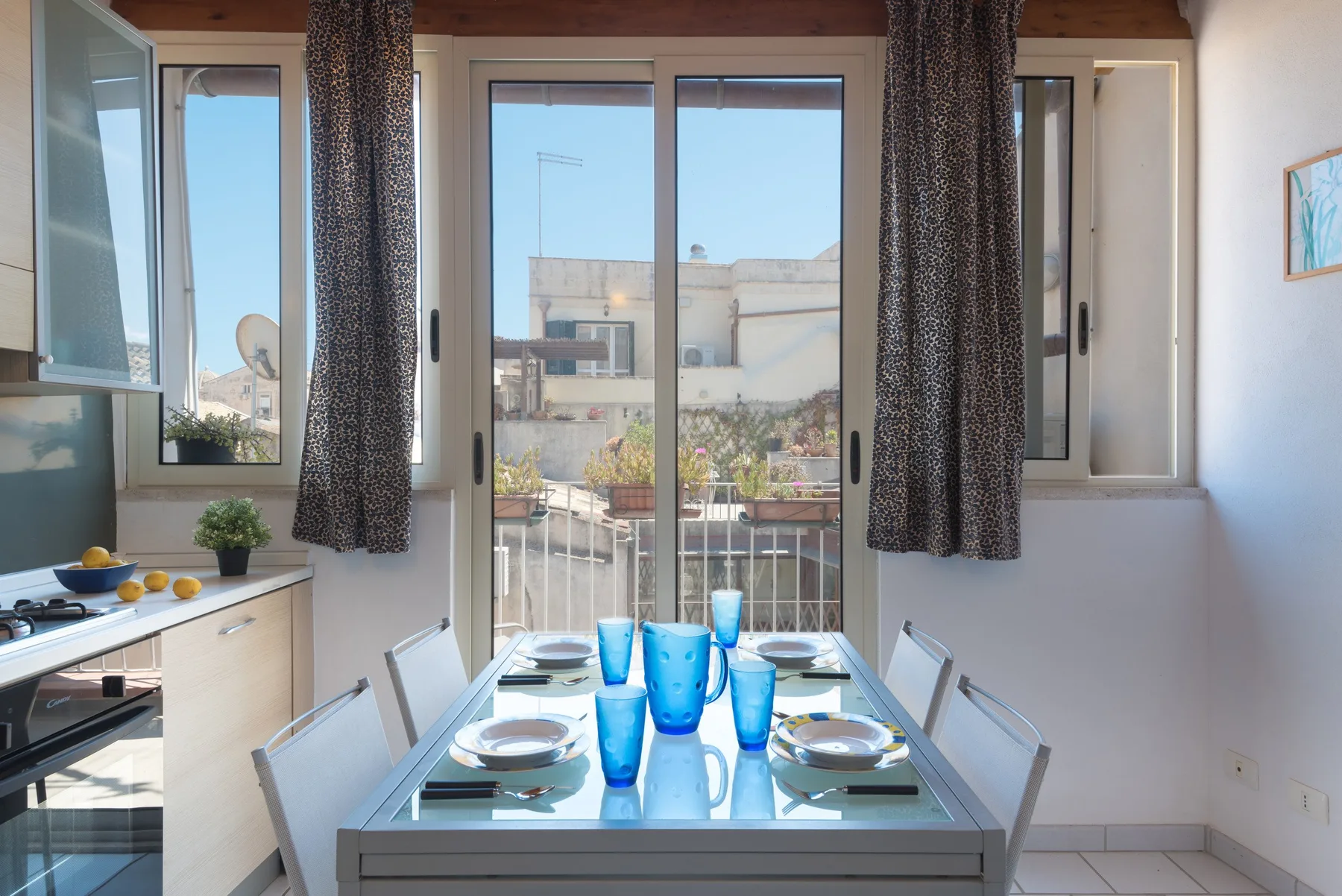A dining area with a glass table set beside large windows and a balcony.