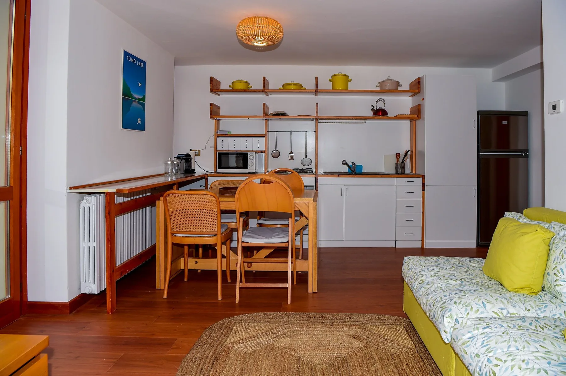 A dining and kitchen area with a wooden table and built-in shelving.