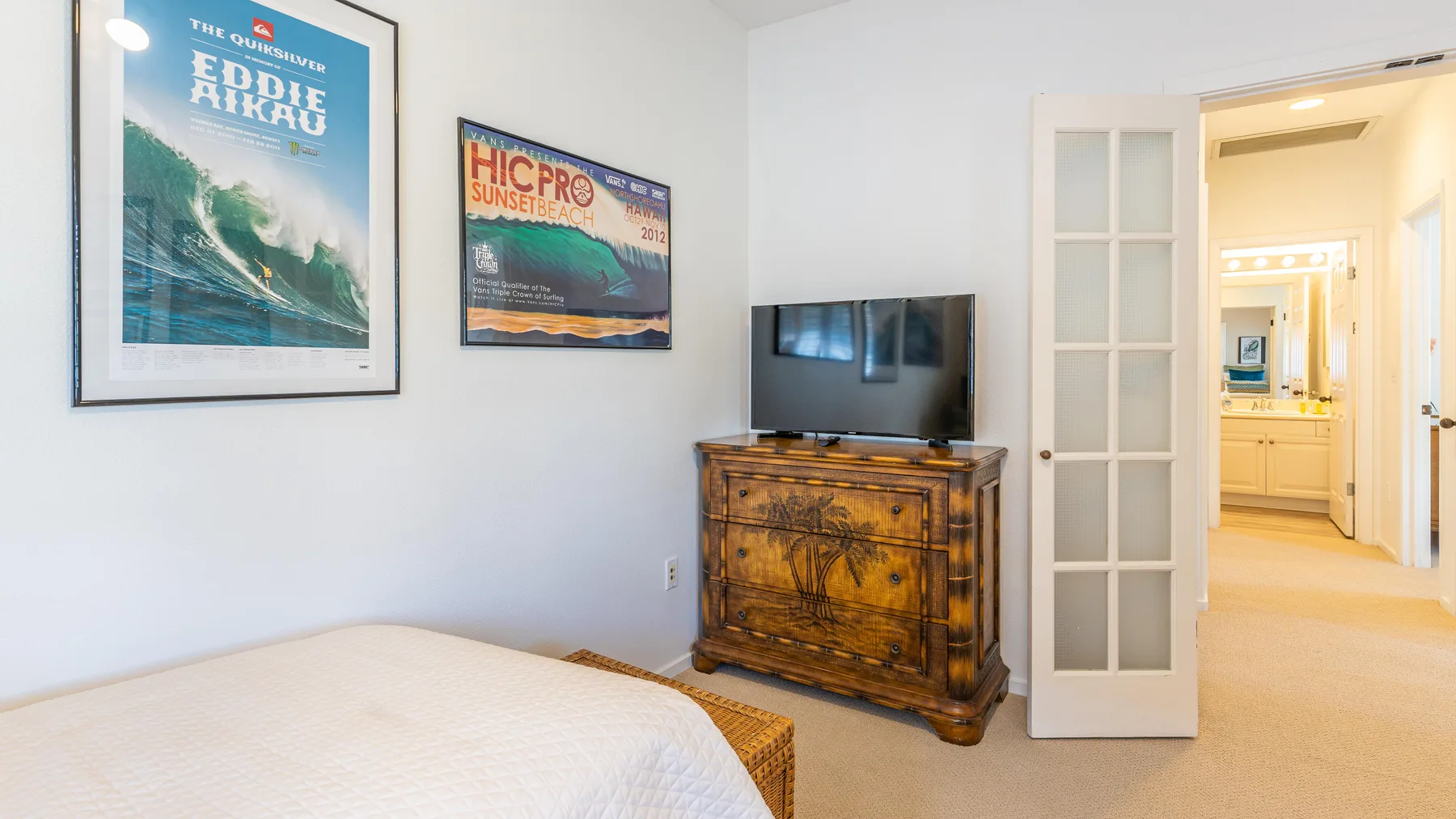 Un dormitorio con una cama, un televisor y una cómoda de madera.