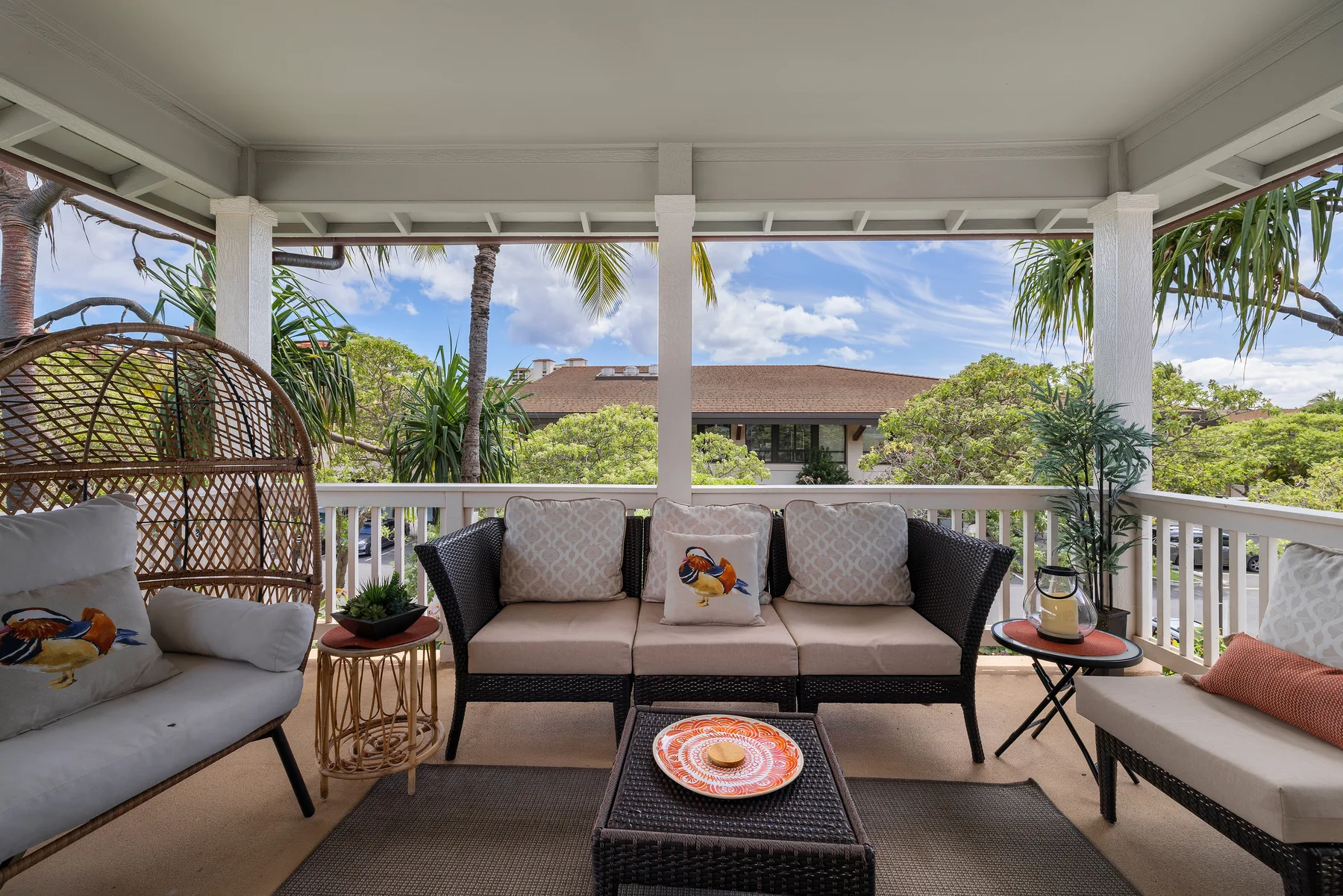 Una zona de estar exterior cubierta con asientos acolchados y vistas a la vegetación tropical.