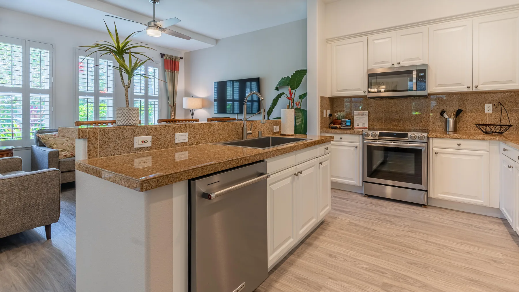 Una cocina luminosa tiene gabinetes blancos, una isla central y electrodomésticos de acero inoxidable.