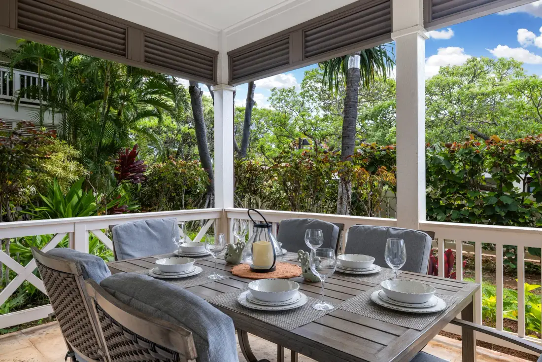 Comedor exterior cubierto con una mesa puesta y vistas a una frondosa vegetación.