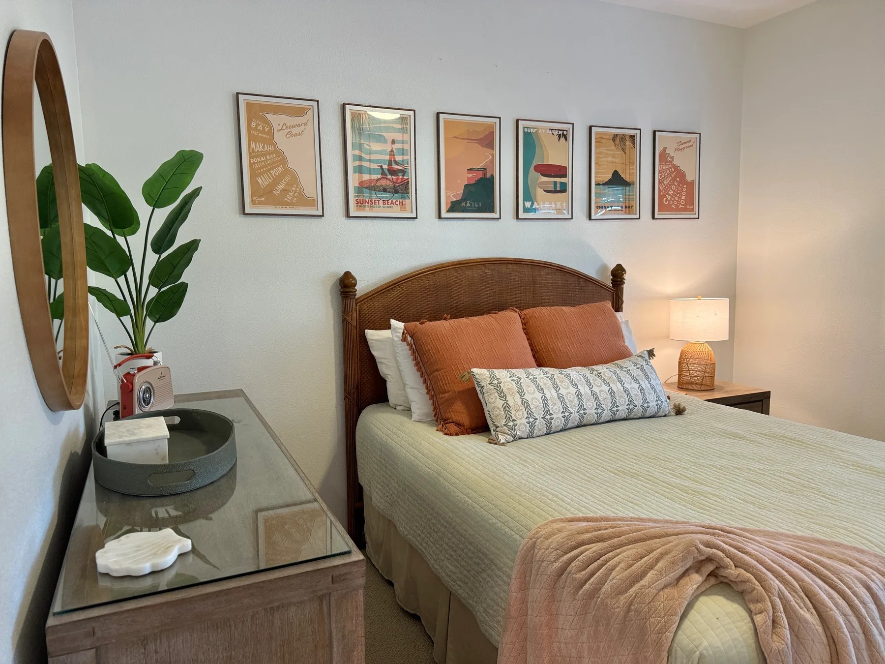 Un dormitorio con una cama de madera, láminas enmarcadas y una lámpara de noche.