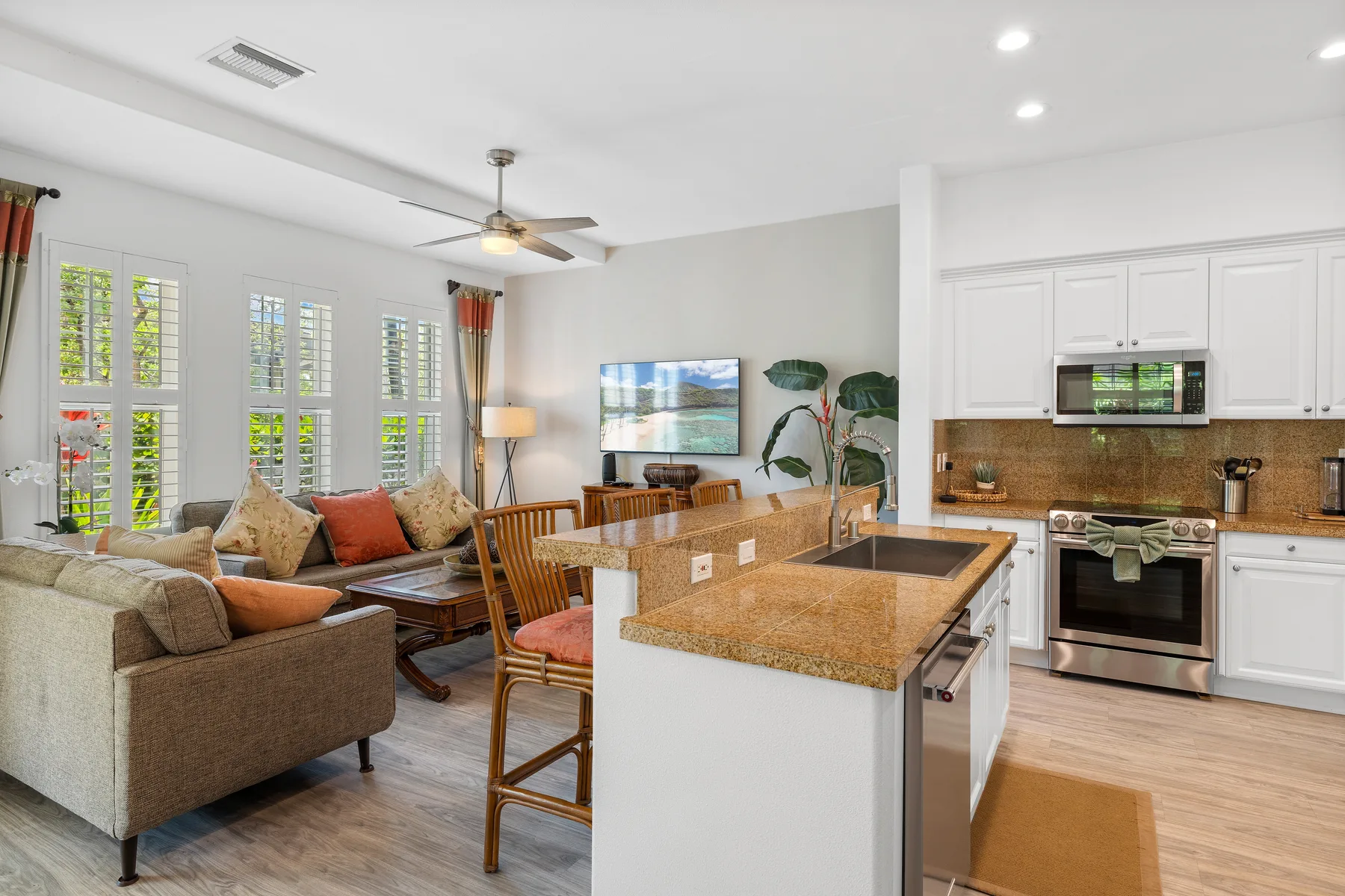 Sala de estar y cocina de planta abierta con sofá, isla y televisor.