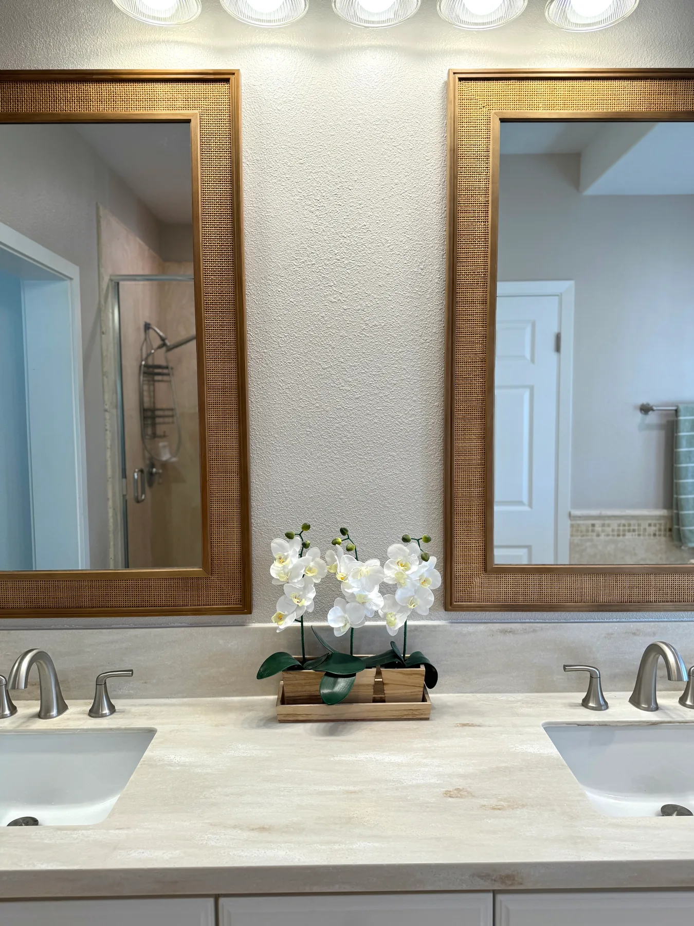Un tocador de baño con dos lavabos, espejos enmarcados y un arreglo floral.