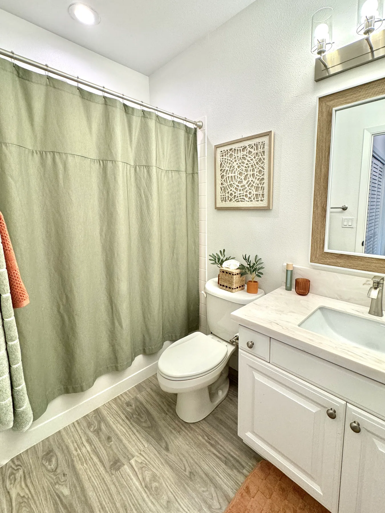 Un baño con cortina de ducha, inodoro y lavabo con mueble.