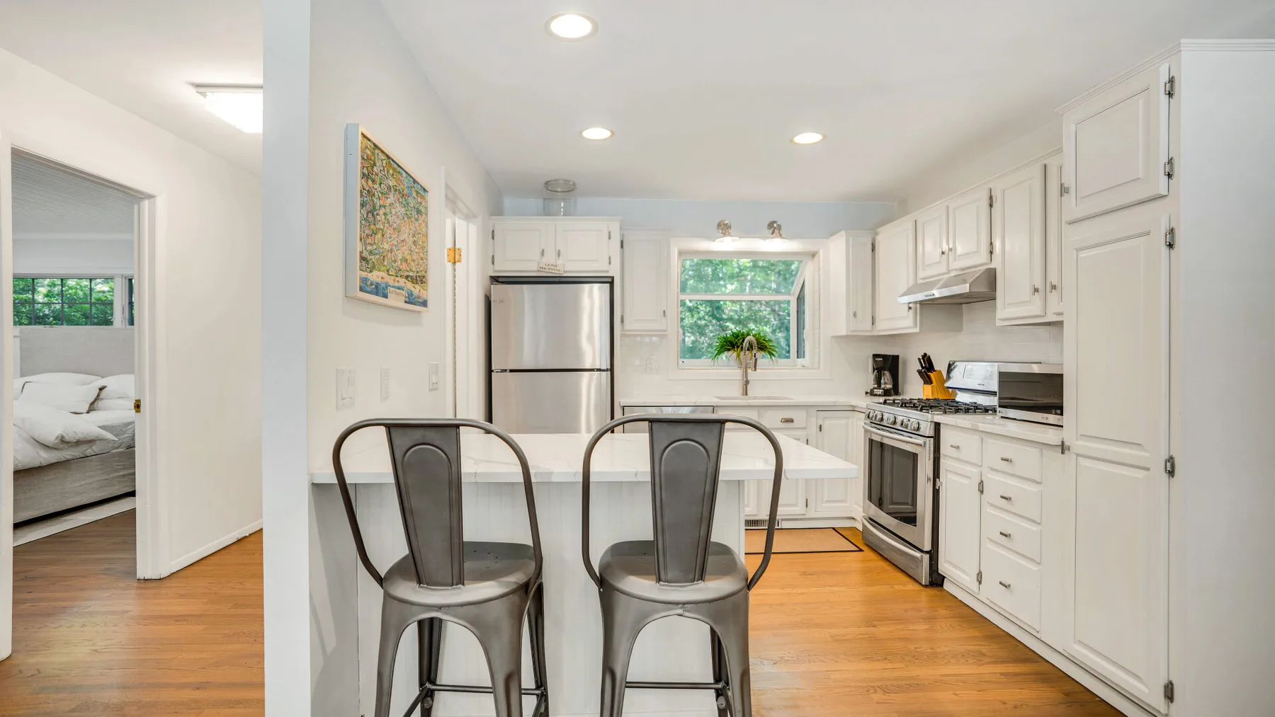 Una cocina luminosa con una barra y dos taburetes metálicos.