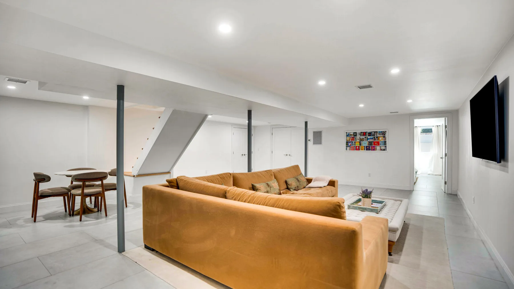 Una sala luminosa con un sofá seccional color canela y una mesa de comedor.