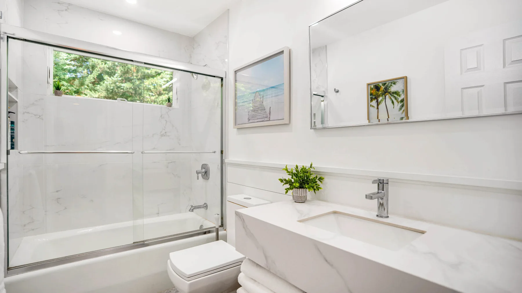 Un baño luminoso con una ducha de vidrio y un amplio lavabo.