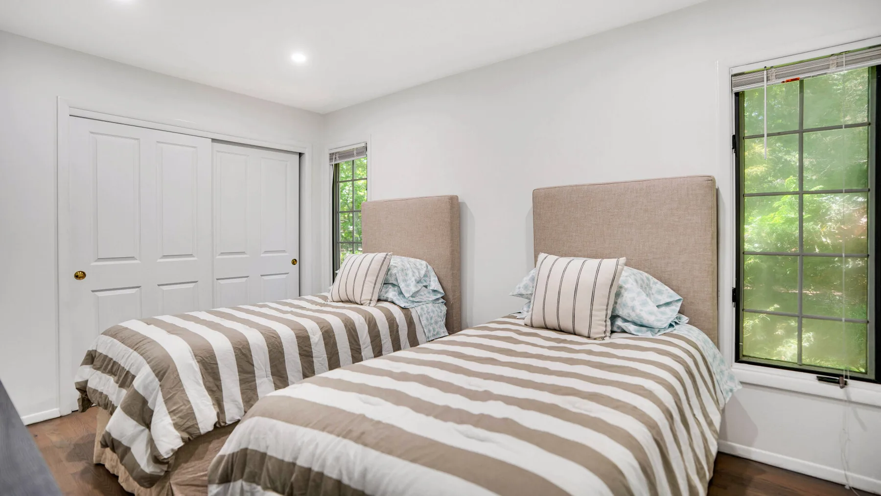 Un dormitorio luminoso con dos camas vestidas con ropa de cama a rayas.