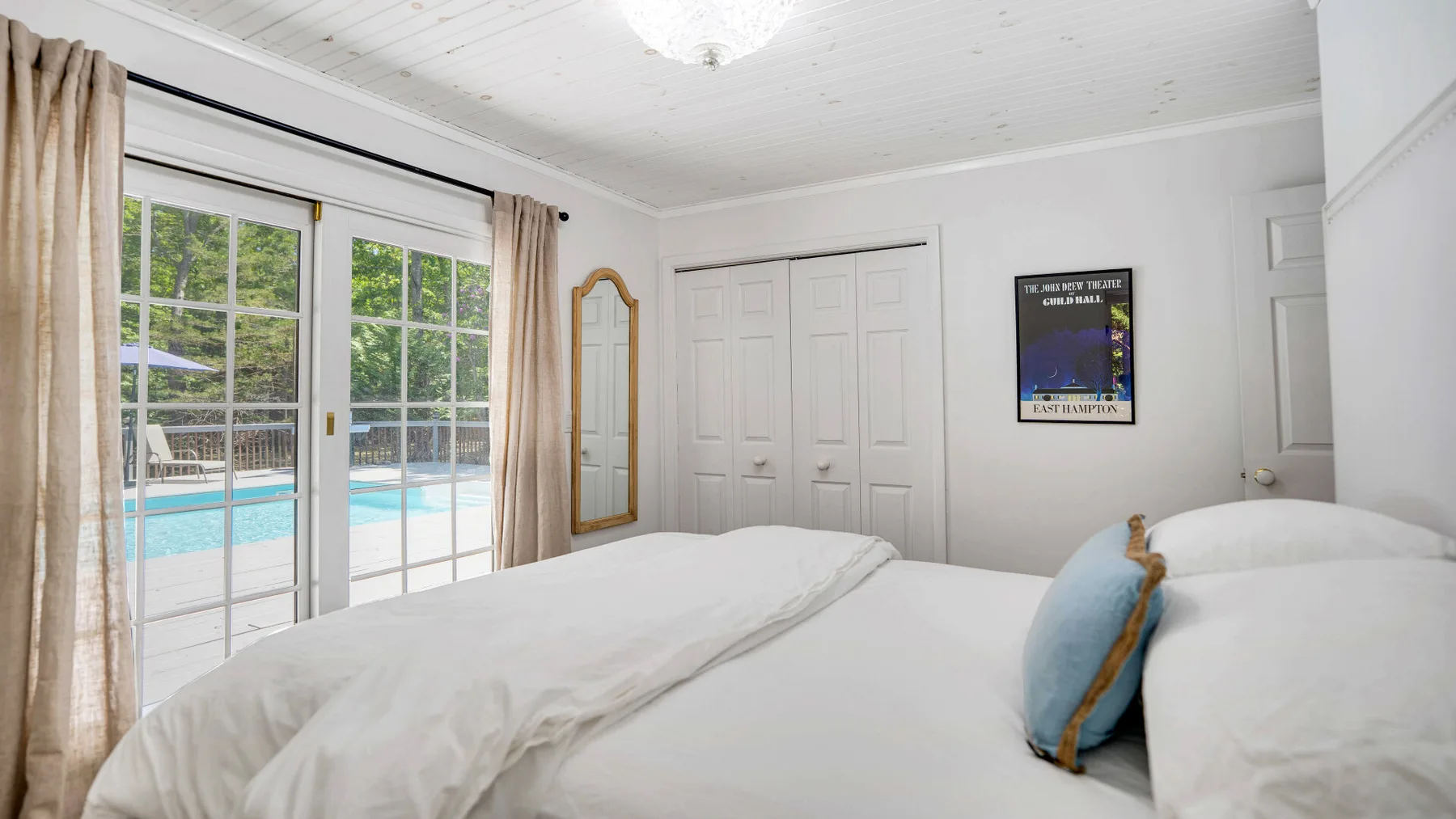Un dormitorio con una cama, puertas corredizas de vidrio y una piscina al exterior.