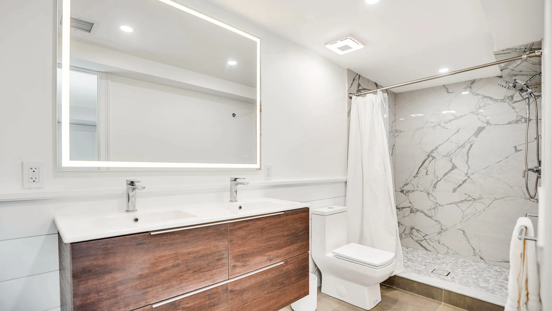 Baño con lavabo doble, inodoro y ducha.