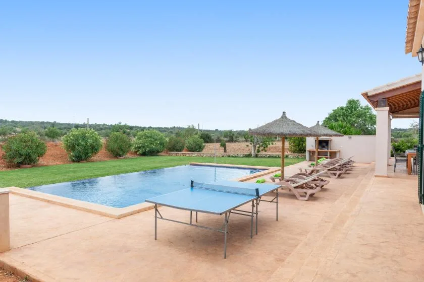 Una zona de piscina al aire libre con una mesa de ping-pong y asientos.