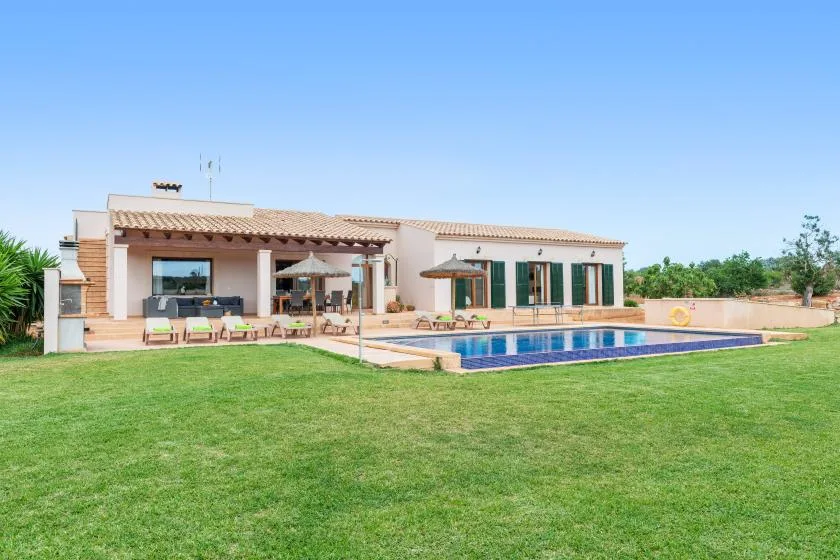 Una casa da a un jardín de césped y una piscina.