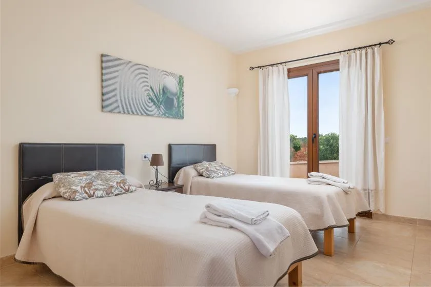 Un dormitorio con dos camas, mesitas de noche y una ventana con cortinas.