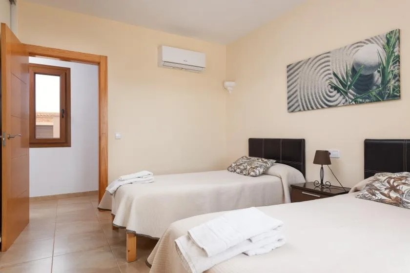 Un dormitorio con dos camas, toallas dobladas y un cuadro.