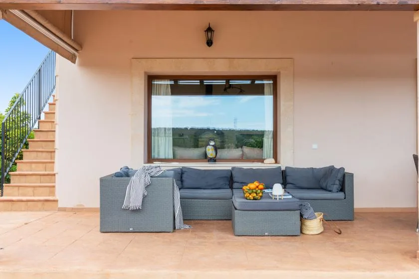 Una zona de estar en un patio cubierto con una mesa baja frente a una ventana grande.