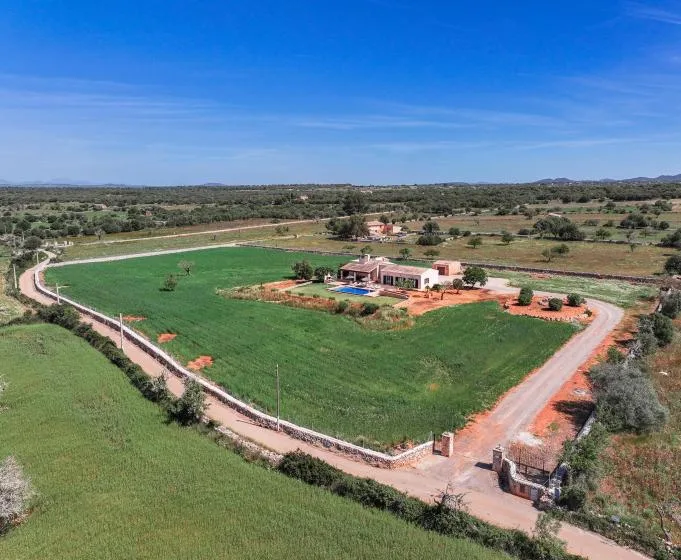 Vista aérea de una propiedad rural rodeada de campos verdes y caminos de tierra.