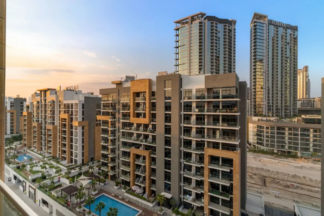 Edificios de apartamentos modernos dan a un patio ajardinado con una piscina.