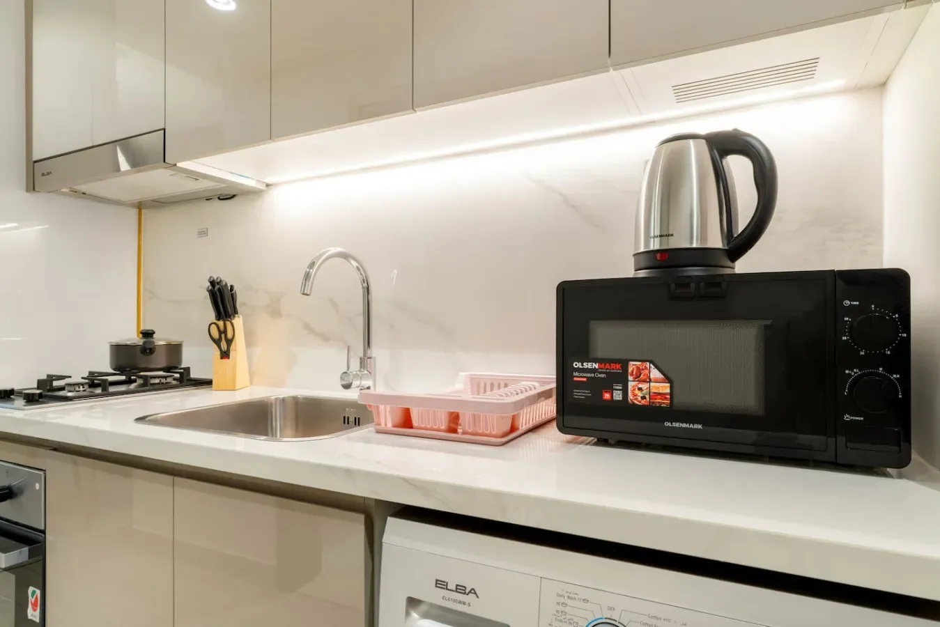 Una encimera de cocina moderna con fregadero, estufa y electrodomésticos.
