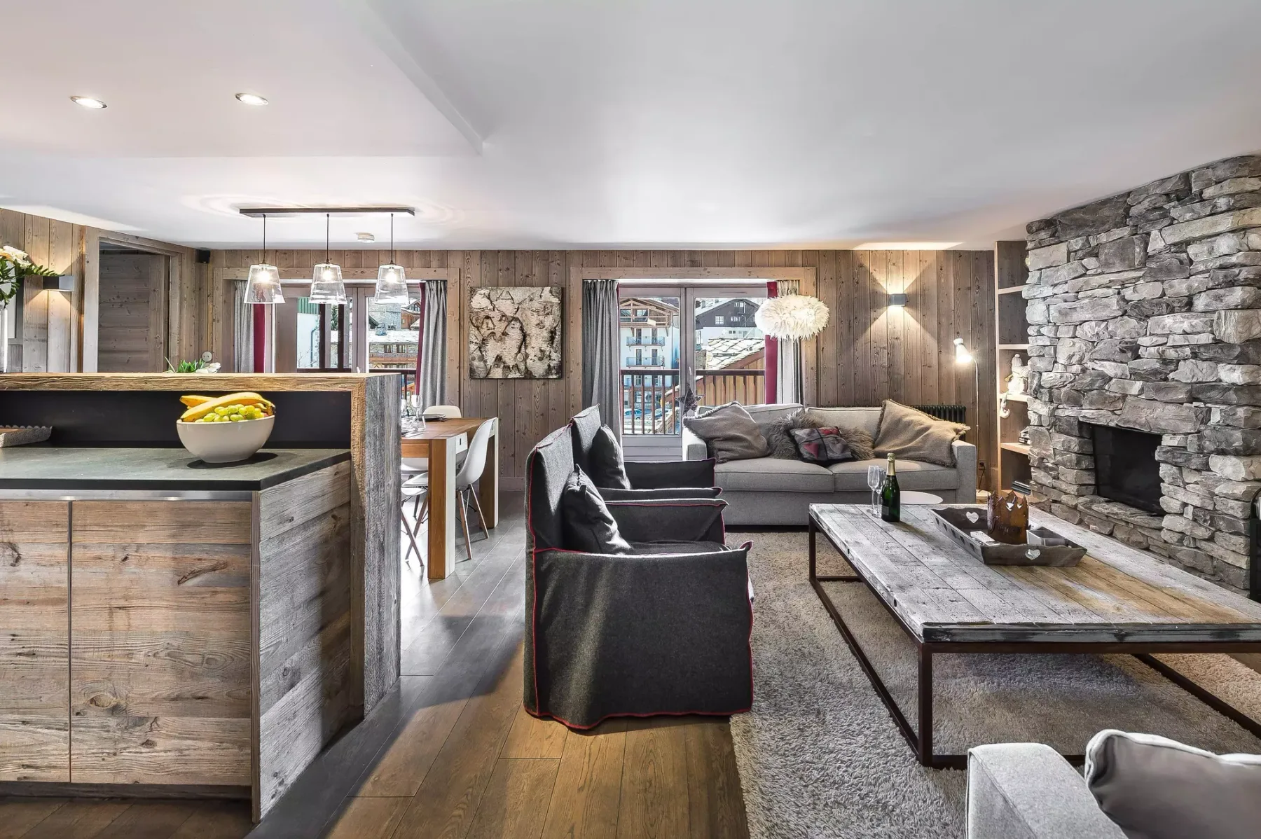 A living room with seating around a coffee table beside a stone fireplace.