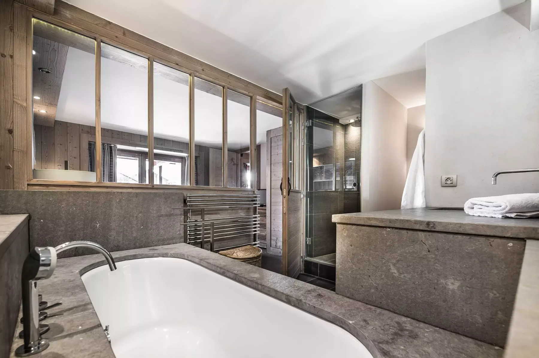 Un baño con bañera, ducha de cristal y lavabo de piedra.