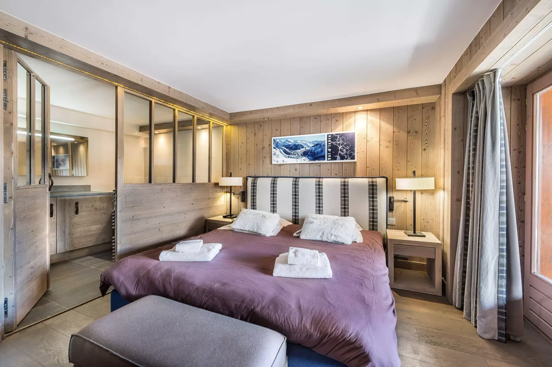 Un dormitorio con una cama doble, mesitas de noche y paredes revestidas de madera.