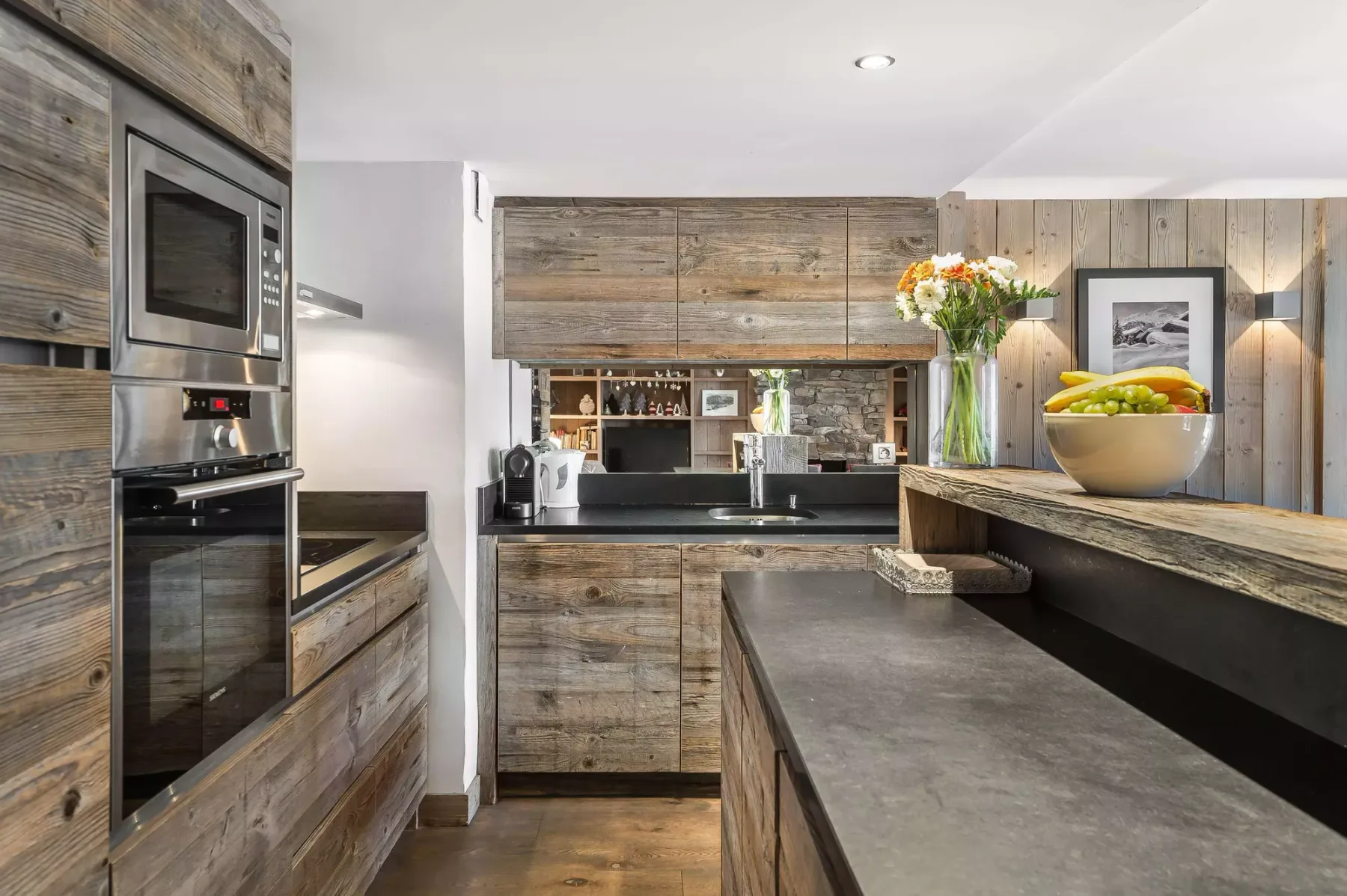 A modern kitchen with wood cabinetry, dark countertops, and a central island.