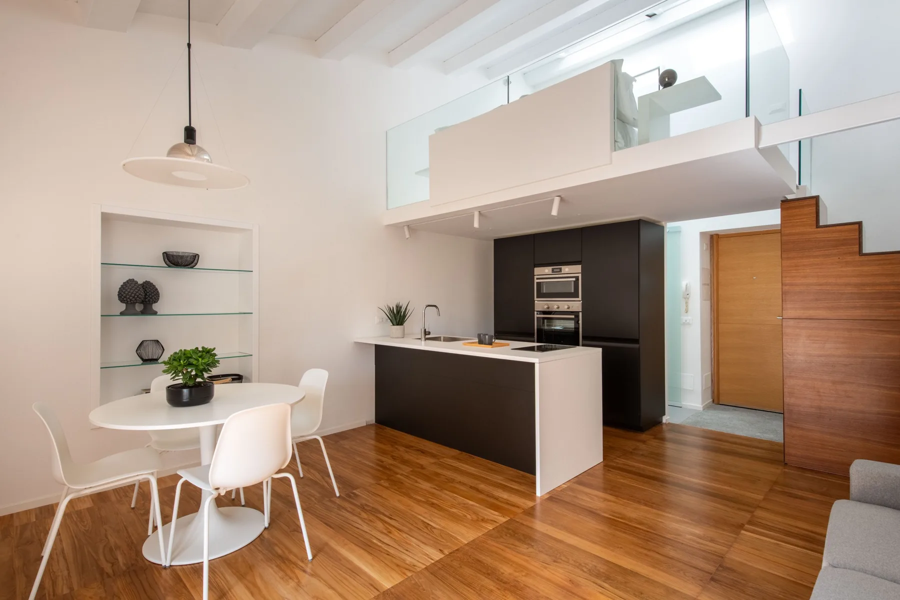 An open-plan kitchen and dining area with a white table and dark cabinetry.